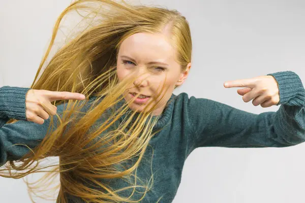 Angry young woman pointing with fingers. Frustrated face expression, hair blowing.