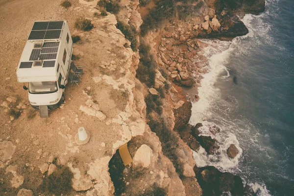 Caravan with solar panels on roof camping on cliff sea shore. Mediterranean region of Mazarron in Murcia, Spain.