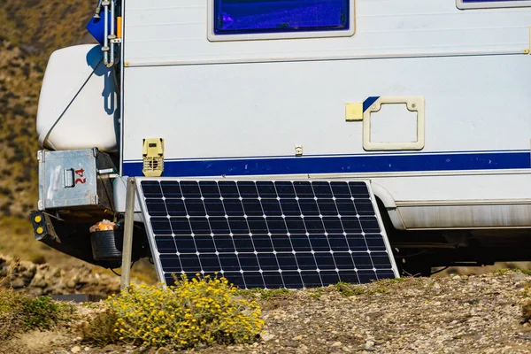 Portable solar photovoltaic panel, charging battery at camper vehicle. Power generation in vacation caravan trip.