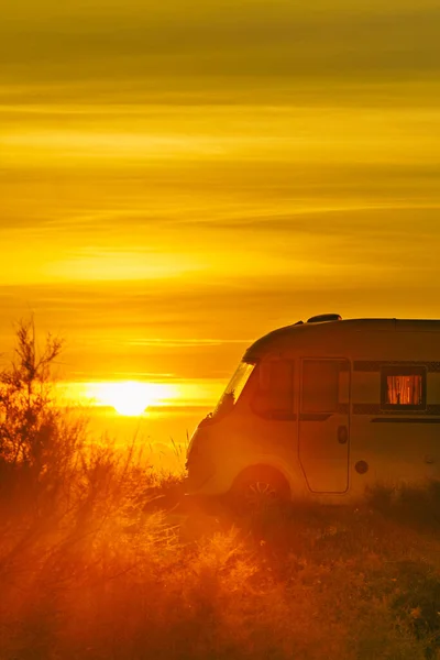 Sun rising over sea horizon and camper rv camping on beach seashore. Holidays in Spain, travel with motor home.