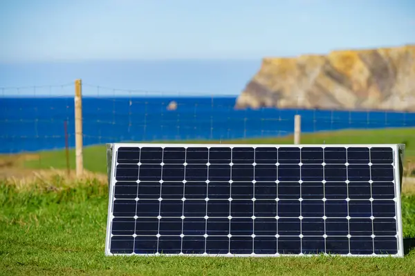 Single solar photovoltaic panels, charging batteries outdoors against sea landscape. Camping trip. Renewable eco energy concept