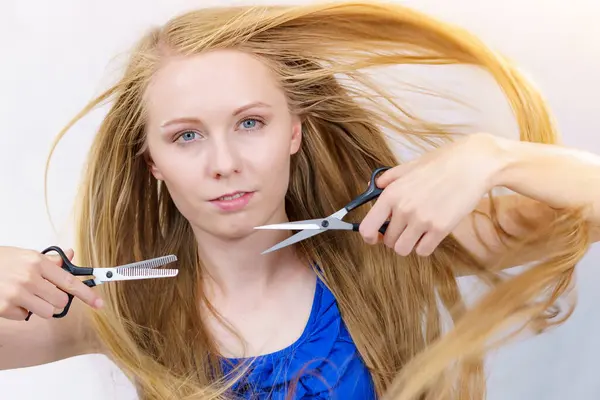 留着长长的金黄色头发的女孩拿着剪刀 展示工作工具 正常的和分块的剪子 做发型 新发型 理发概念 — 图库照片