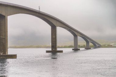 BGimsoystraumen bridge over fjord on Lofoten islands. Summer time, foggy hazy day, overcast weather. clipart