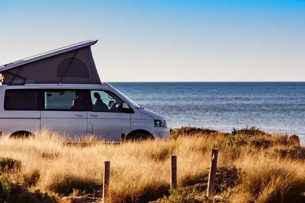 露天帐篷顶的野营车在地中海沿岸露营 假日和驾车回家旅行 图库照片