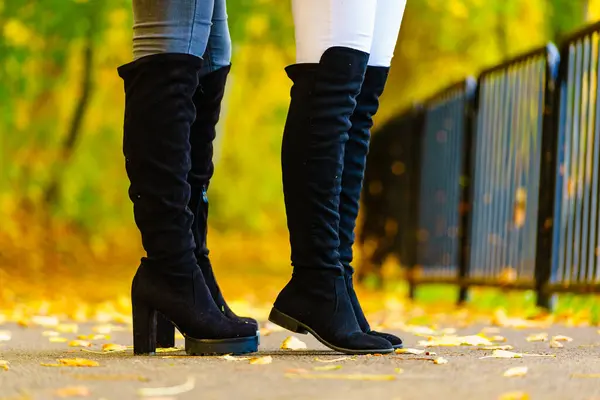 两个穿着黑色长腿膝盖长靴和牛仔裤的女人是难以辨认的 温鞋靴 免版税图库图片