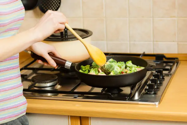 キッチン料理の女性は 鍋や試飲で冷凍野菜を炒めます おいしい夕食の食事を作る女の子のフライ ストック画像