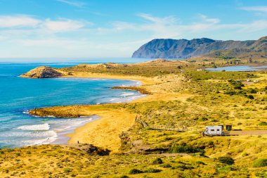 Sea coastal landscape with camper rv camping on beach in the distance. Spain Murcia region, Calblanque Nature Park. clipart