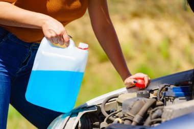 Woman pouring blue antifreeze liquid for car windshield screen washing with bootle watering can clipart