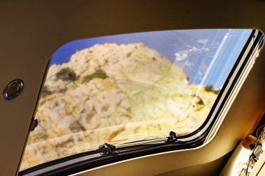 View from inside on mountain nature through sunroof, panel window on roof top of rv camper vehicle. Traveling by motor home. clipart