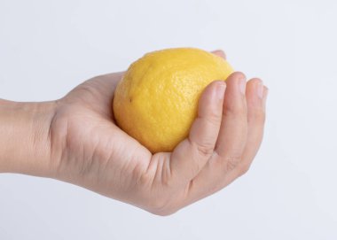 Beyaz arka planda taze limon tutan el kadını.