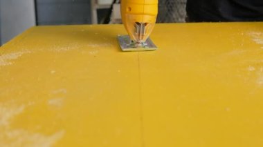 Ahşap işçisi sarı kalas işçiliğini kesmek için bir yapboz kullanıyor.