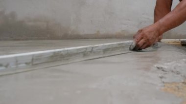 Becerikli adam beton zemini yıkıyor.