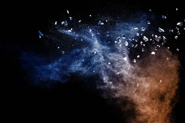 stock image Split debris of  stone exploding with blue powder against black background.