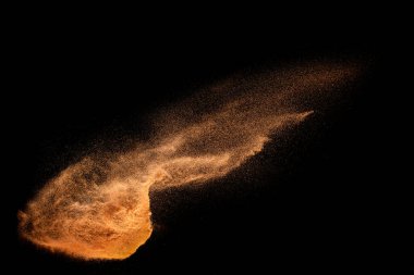 Kahverengi kum patlaması siyah arka planda izole edildi. Kumlu tozun dondurucu hareketi sıçrıyor.