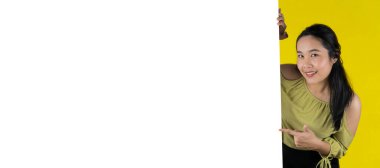 Genç çekici Asyalı kadın boş beyaz tahtayı gösteriyor ve tutuyor, mesajınızı girmek için boş tahtayı gösteriyor. Güzel bir iş kadını boş bir ilan panosu gösteriyor, sarıda izole edilmiş, kopyalama alanı..