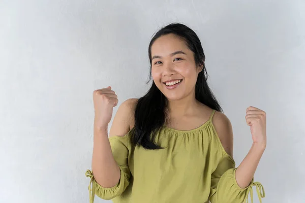 Great Offer. great deals An Asian girl in a cheerful green shirt points to a handful of invisible objects. pose over a gray background