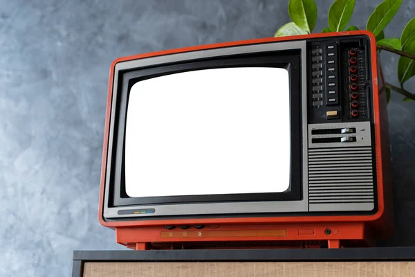Old orange TV on a wooden cabinet in the room of the house, white background screen. Loft wall. Warm atmosphere. vintage set of tv equipments concept.