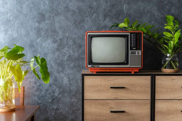 Old TV on a wooden cabinet in the room of the house. Loft wall. Warm atmosphere. vintage set of tv equipments concept.
