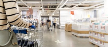 Soft focus woman with shopping cart at store, for furniture in warehouse. Many big metal shopping carts for the interior furniture on a parking lot for the customer use shopping in the warehouse store.