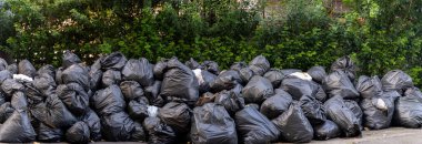 Torbalar dolusu plastik atık, çöp yığını, bir sürü çöp yığını yığılmış çöp yığını yığılmış çöpler, ağaçların duvarlarına siyah çöp torbaları, çöplerden gelen kirlilik....