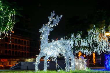 Parlak Noel süslemeleri gece dışarıda. Ren geyiği ailesi. Sokakta Noel süsleri. Parlayan Noel ışıklarından yapılmış bir geyik. Şenlik Dekoru.