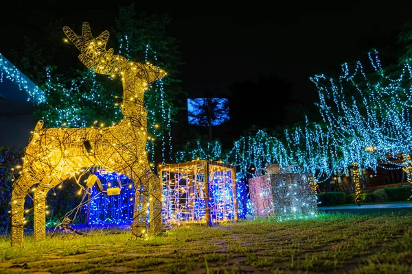 Sparkling figurine of Christmas Deer. Gold Christmas garland. Illumination at night. Winter festival. Holiday lights in form of deer on street. Christmas Eve. Concept of New year.