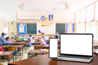 Sınıfın arka planındaki çocuklar. Eğitim yazılımı web sitesi teknoloji reklamları konsepti. Ön manzara, boş siyah dijital dizüstü bilgisayar ve ahşap tabletli akıllı telefon..