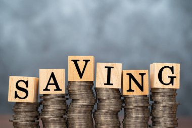 Altın sikkeleri ve ahşap blokları biriktirip karanlık arka plan ve doğal ışıklandırmadan tasarruf etmeye çalışın. Finansal ve yaratıcı konsept