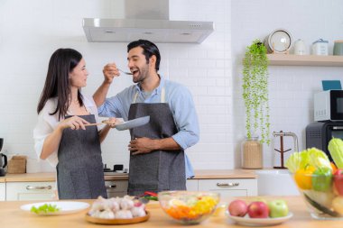 Kız arkadaşının yaptığı yemeğin tadına bakan adam. Genç bir çift güzel bir sabah kahvaltısını hazırlarken eğleniyor. Aşçılık, birlikte, mutfak, ilişki