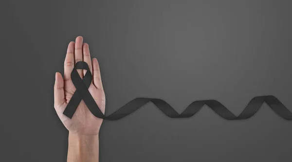 Hand hold black ribbon on background. Mourning is the grieving process. Melanoma and Skin Cancer Awareness Calligraphy Poster Design. Realistic Black Ribbon. May is Cancer Awareness Month