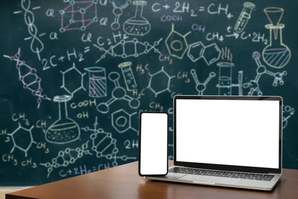 ノートパソコン スマートフォン 空白の画面は フォアグラウンドのための木製のテーブルにあります 分子モデルと式有機化学式緑の黒板の背景に書かれた生化学の科学的背景 — ストック写真