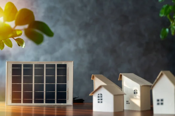 stock image Small cardboard house and solar panels close up. Free space to put text, images, media. Close up view of alternative energy engineer pointing at solar panels for future energy in studio.
