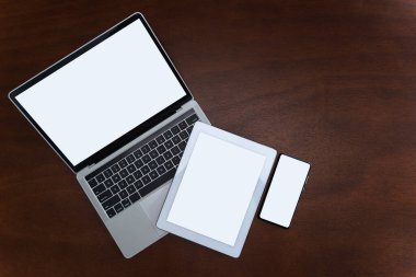 Laptoplar, tabletler ve masada boş ekranları olan akıllı telefonlar günümüzde iletişim teknolojilerinde çok kullanılıyor. Kopyalama alanı olan düz üst görünüm, boş beyaz ekran.