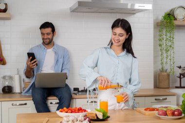 Genç çift mutfakta, laptop ve smartphone kullanarak online evde karısı telefon apps ile yemek aile sabah yaşam tarzı araçlar veya aygıtları bağımlılık kavramı ile süre çalışan adam gülümseyen