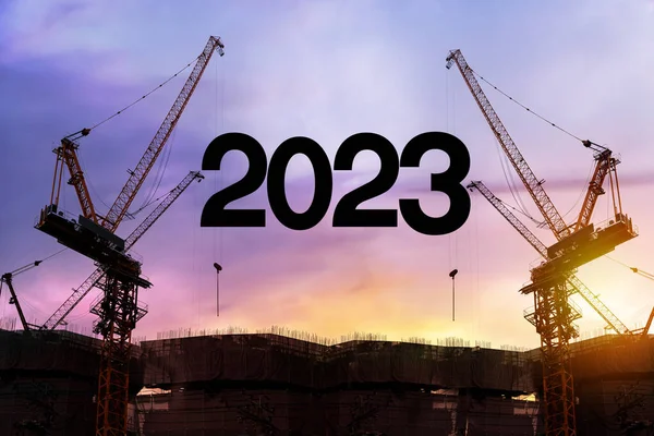 ビルの敷地内に2023年の青写真を探しているビジネスマンエンジニア 歓迎の準備のためのクレーンと曇りの空と建設労働者のシルエット2023新年会と新しいビジネスを変更します — ストック写真