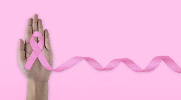 Hands holding pink ribbon on backgrounds. Breast cancer awareness and October Pink day, world cancer day. Top view. Mock up. Pink Breast Cancer Awareness Ribbon.
