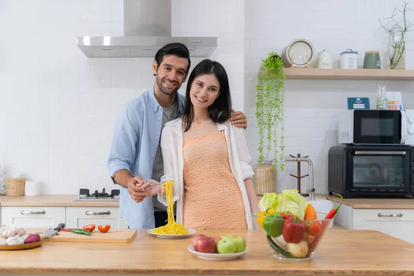 stock image Romantic couple enjoying lunch in the restaurant, eating paste and drinking red wine. Lifestyle, love, relationships, food concept. Happy young man eating spaghetti by cheerful girlfriend at home.