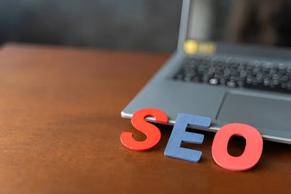 stock image Wooden letter stands for SEO abbreviation lying on laptop at desk. Modern marketing buzzword SEO - Search engine optimisation. Top view on wooden table with blocks. Top view. Close up.