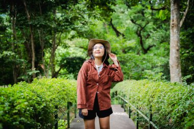 Asyalı genç, güzel bayan sırt çantalı vahşi ormanda tek başına seyahat ediyor. Çekici kız gezgin, tatil gezisi sırasında doğa ormanında mutluluk ve eğlenceyle yürürken etrafına bakar ve keşfederdi..