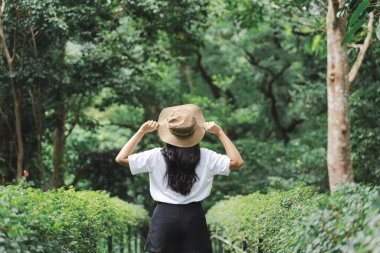 Elinde hasır şapka tutan ve yaz sabahında macera yolculuğuyla Forest Gölü 'nde güneşin doğuşunun keyfini çıkaran genç bir kadın.