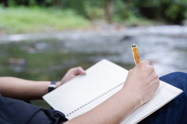 İnsanların, kamp alanında kitap yazarken defter fikirleri yazıp doğanın tadını çıkardıkları görüntüler. Nesneye seçici odak, arka görünüm, boşluğu kopyala.