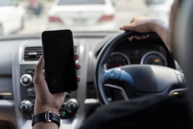 Bir arabanın içinde cep telefonu kullanan bir adam modeli. Sürücü elinde boş siyah ekran akıllı telefon, arama adresi ve harita navigatör uygulaması, ulaşım teknolojisi ile lokasyon.