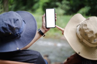 Kadın ve erkek, ellerinde telefon, ellerinde cep telefonu olan kadın ve erkek, yeşil tropikal yağmur ormanı manzarasına bakıyor..