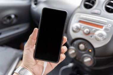 Genç adam arabada akıllı cep telefonu kullanıyor. Manzarayı kapat. Adam elini kapar ve arabadaki cep telefonunu şarj eder. Model boş arkaplan