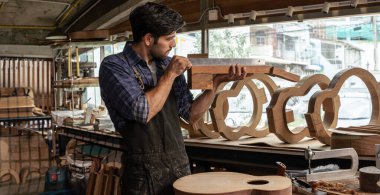 Bir Luthier atölyesindeki içi boş bir gitar yakasını kontrol edip hizayı, insan sanatları ve el sanatları kavramını doğruladı. Gitar ve ahşap üzerinde çalış..