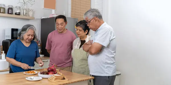 Group of senior friends at home cooking dinner party. Happy senior people group having fun at pic nic barbecue garden diner. Food life style concept with mature friends cooking.