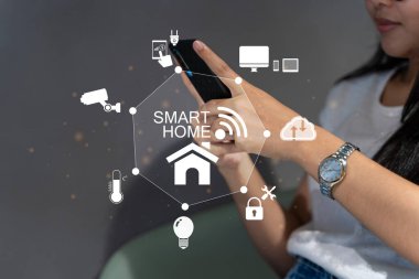 Yatak odasında akıllı telefon tutan bir kadının ellerinde akıllı ev arayüzü ve otomasyon konsepti var. Akıllı ev otomasyon kontrol sistemi. İnternet teknolojisi yeniliği, ağ kavramı.