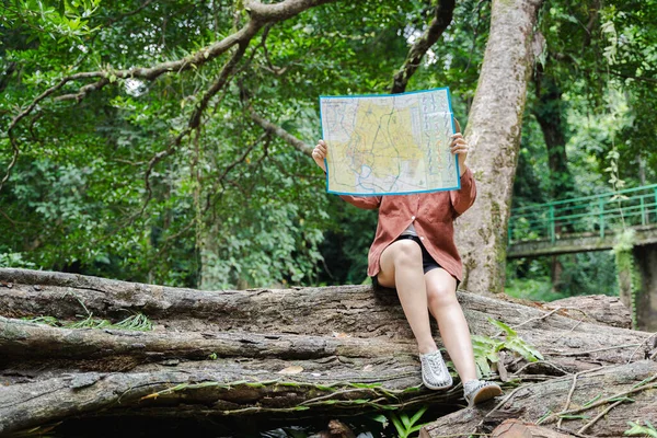 Woman hiking and looking at map outdoors in nature. Travelers explore the mountainous forest map. Woman red plaid shirt holding a map in the forest.