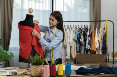 Mutlu gülümseyen Asyalı yaratıcı moda tasarımcısı terzi dükkanında çalışıyor. Kadın yeni kıyafet koleksiyonu kavramı yaratıyor.