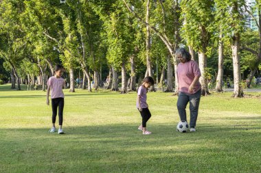 Torunu parkta futbol oynarken sağlıklı ve mutlu bir büyükanne. Dedelerin genç bir kızla vakit geçirmesi kavramı.